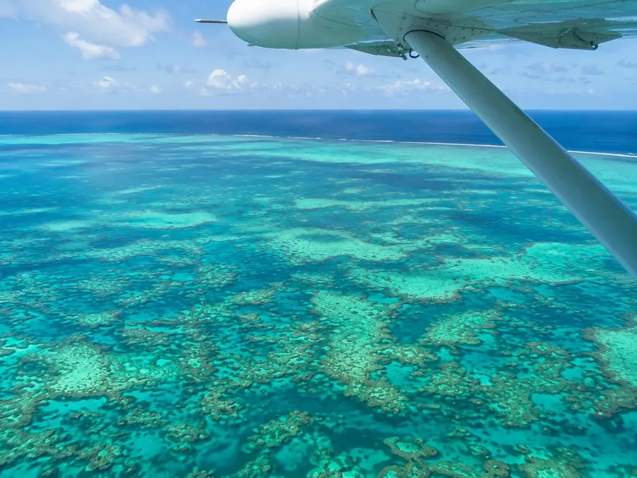 The view from under the wing on a low pass over a coral reef and the deep water edge