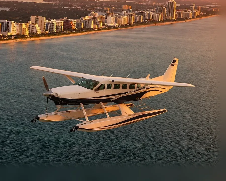 A seaplane on floats tracking the Miami Beach shoreline in low golden evening light